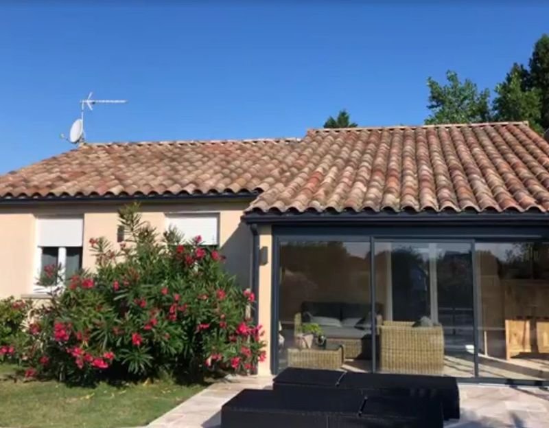Toiture en tuiles canal patinées au-dessus d’une véranda, maison entièrement rénovée
